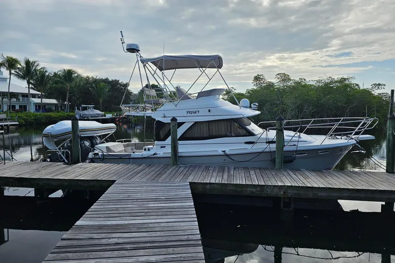Slide: The Image of 2022 Cuwater C-32-CB boat docked by a wooden pier, surrounded by lush greenery. - 4
