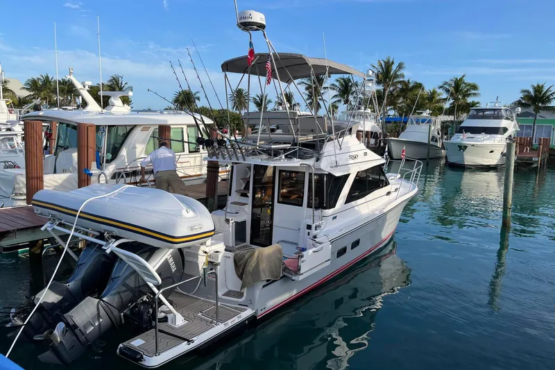 Slide: The Image of 2022 Cuwater C-32-CB boat docked in a marina with fishing rods and inflatable dinghy. - 51