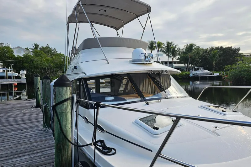 Slide: The Image of 2022 Cuwater C-32-CB boat docked by a wooden pier, surrounded by lush greenery. - 9