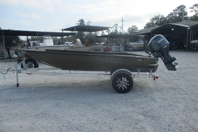 Slide: The Image of 2026 Avid 16 Commander boat on trailer with Yamaha outboard motor in a gravel lot. - 1