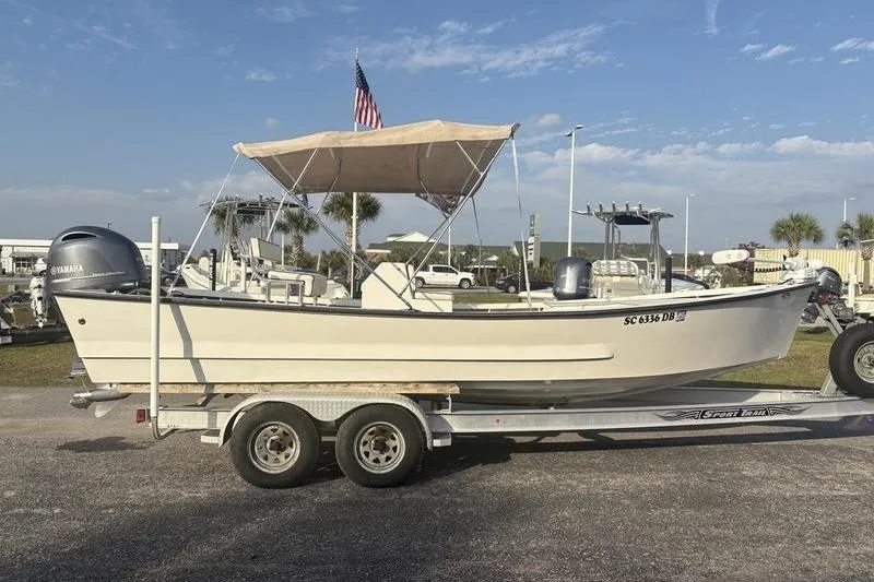 Slide: The Image of 2014 Reno 23 boat on trailer with canopy and American flag, parked outdoors. - 4
