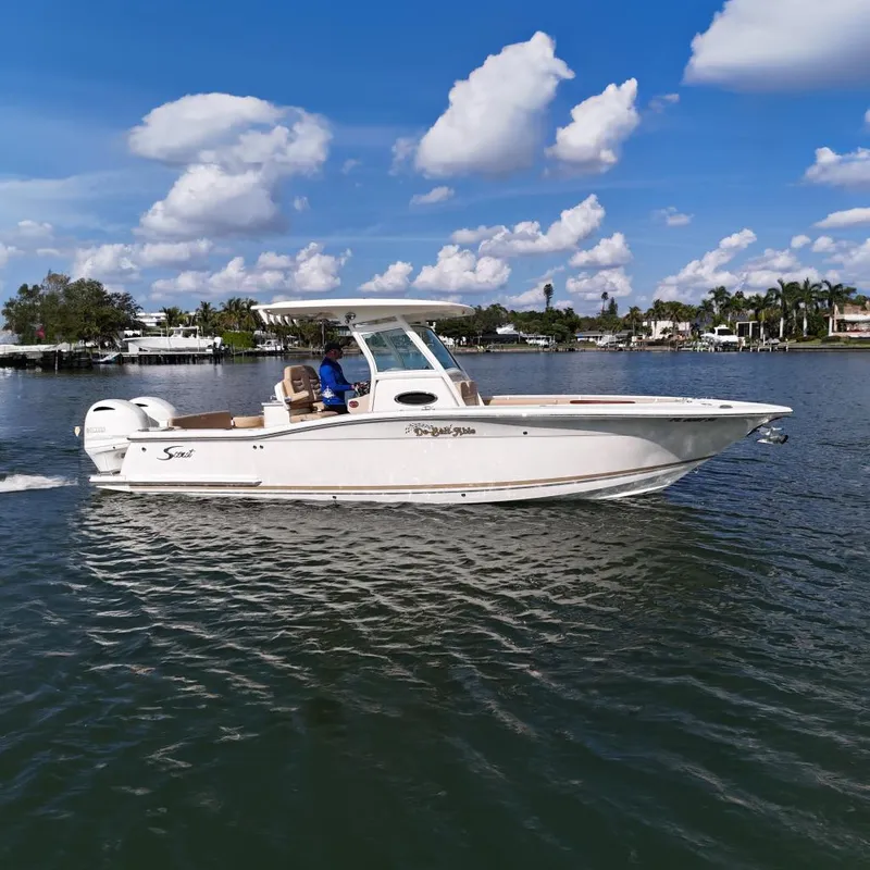 The Image of 2019 Scout 275 LXF boat cruising on a sunny day with scenic waterfront background. - 0