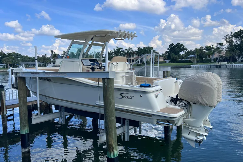 Slide: The Image of 2019 Scout 275 LXF boat on lift, docked by waterfront homes under blue sky. - 10