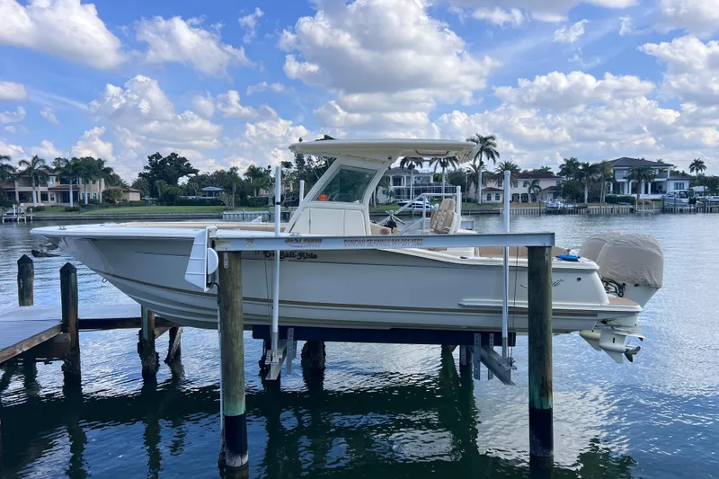 Slide: The Image of 2019 Scout 275 LXF boat docked on a lift, with scenic waterfront background. - 11