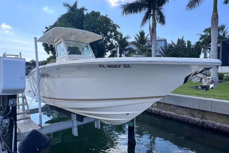 Slide: The Image of 2019 Scout 275 LXF boat docked near palm trees and waterfront homes. - 15