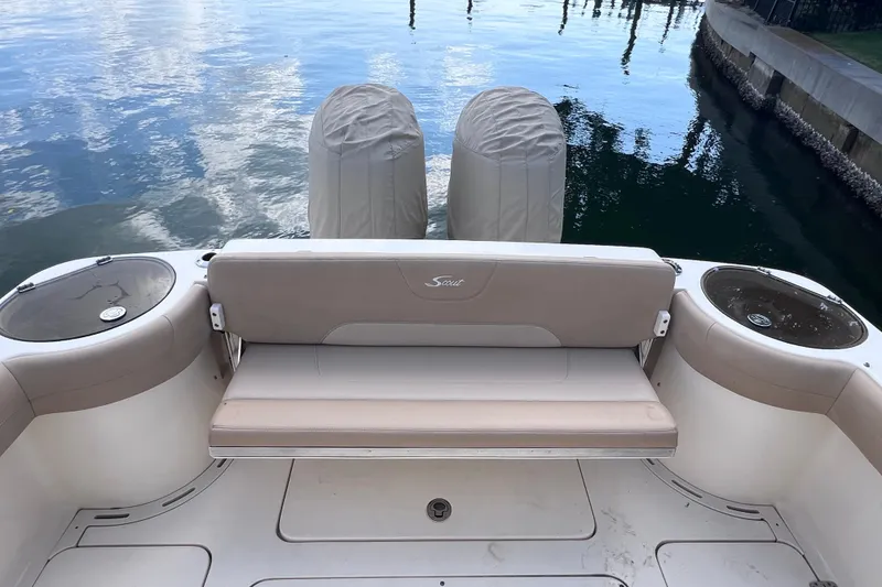 Slide: The Image of 2019 Scout 275 LXF boat with covered engines and seating, docked by calm water. - 18