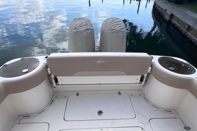 Slide: The Image of 2019 Scout 275 LXF boat interior with dual covered engines, docked by calm water. - 19