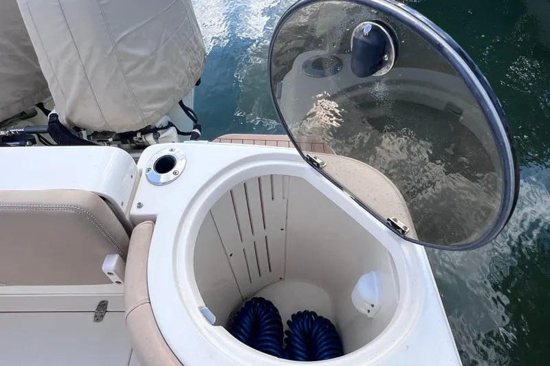 Slide: The Image of Open storage compartment on 2019 Scout 275 LXF boat with coiled blue hose. - 23