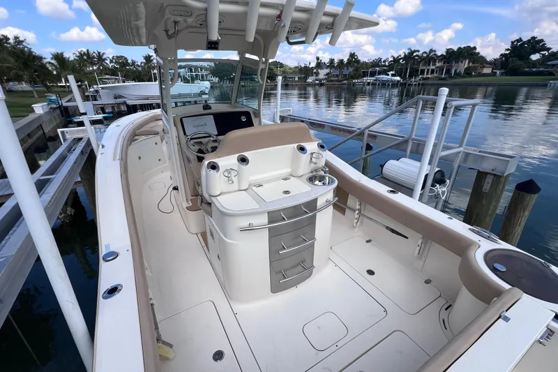 Slide: The Image of 2019 Scout 275 LXF boat docked by a serene waterfront with clear skies. - 25