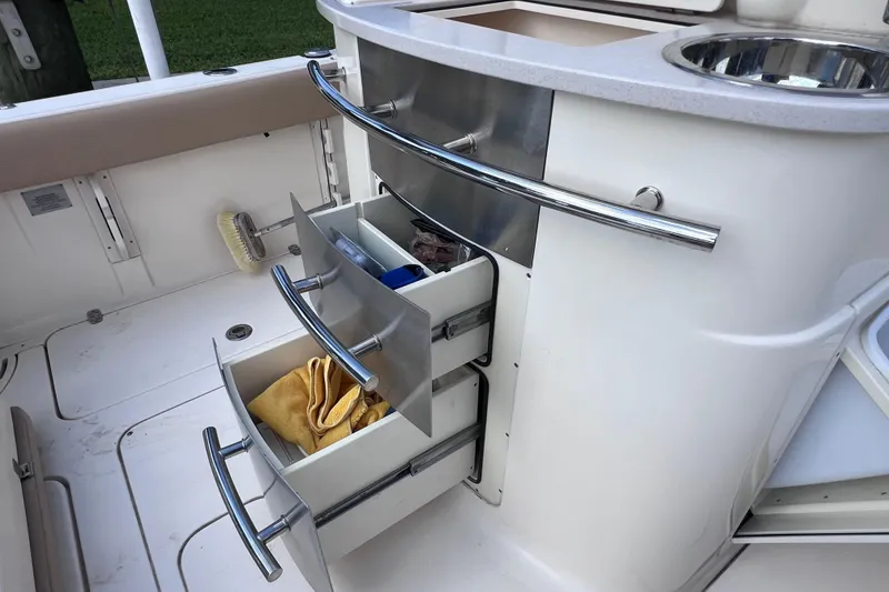 Slide: The Image of 2019 Scout 275 LXF boat interior with open storage drawers and sink. - 28