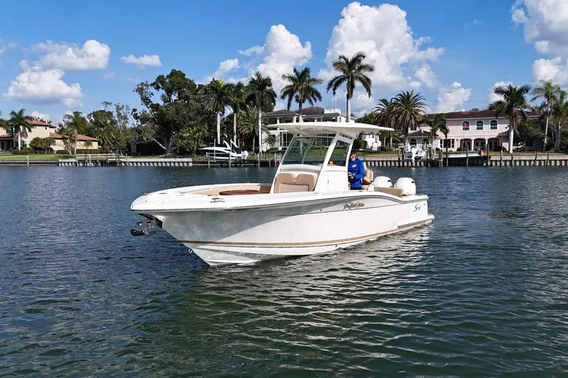 Slide: The Image of 2019 Scout 275 LXF boat cruising on a sunny day near waterfront homes. - 3