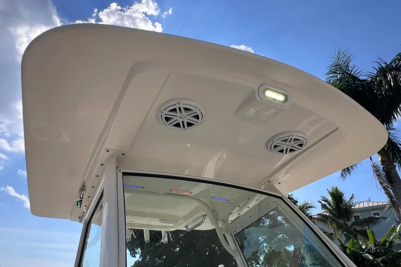 Slide: The Image of 2019 Scout 275 LXF boat roof with speakers and lights under clear blue sky. - 34