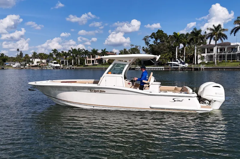 Slide: The Image of 2019 Scout 275 LXF boat cruising on a sunny day, surrounded by waterfront homes and palm trees. - 4