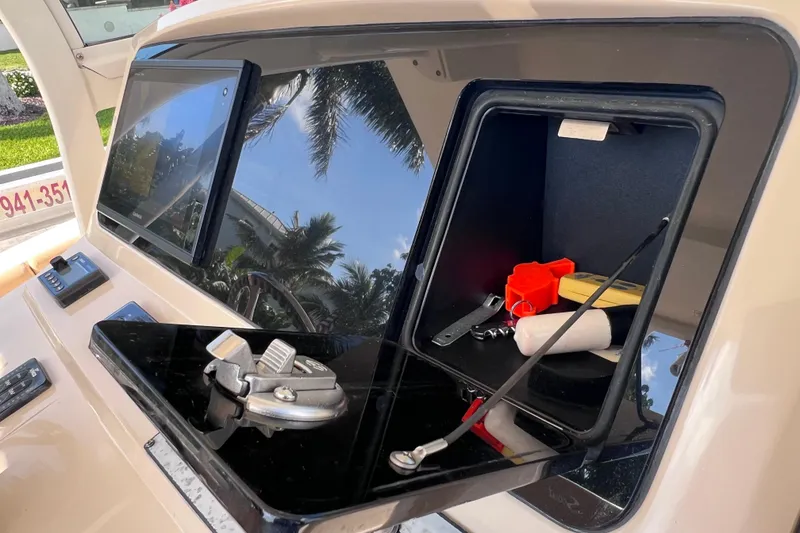 Slide: The Image of 2019 Scout 275 LXF boat dashboard with open storage compartment and visible controls. - 46