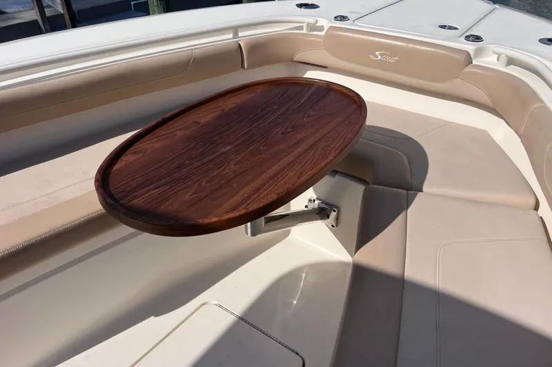 Slide: The Image of 2019 Scout 275 LXF boat interior with wooden table and beige seating. - 59