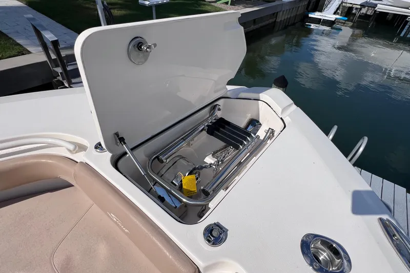 Slide: The Image of 2019 Scout 275 LXF boat with open storage compartment and ladder by the water. - 65