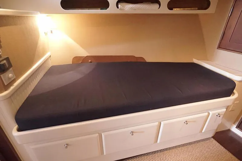 Slide: The Image of Interior cabin bed on 2003 Huckins 44 Atlantic yacht, featuring storage drawers and cozy lighting. - 34