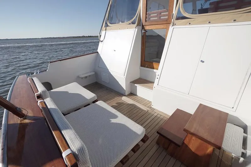 Slide: The Image of 2003 Huckins 44 Atlantic yacht deck with cushioned seating and wooden accents. - 8