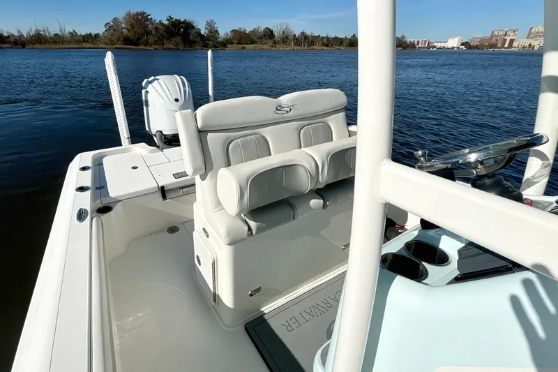 Slide: The Image of 2022 ShearWater 250 XTE boat interior with seating and steering wheel on a calm lake. - 11