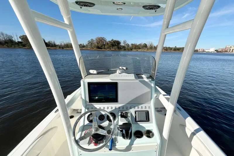 Slide: The Image of 2022 ShearWater 250 XTE boat console with steering wheel and navigation system on calm water. - 13