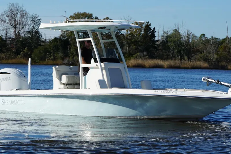 Slide: The Image of 2022 ShearWater 250 XTE boat cruising on a calm river with trees in the background. - 7