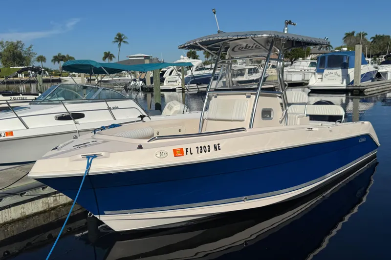 Slide: The Image of 2007 Cobia 237 Center Console boat docked in a marina, clear blue sky. - 2