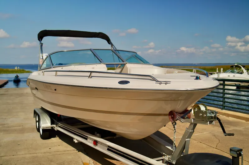 Slide: The Image of 1995 Sea Ray 200 Bow Rider boat on trailer by the water, sunny day. - 2