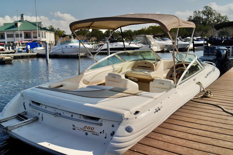 Slide: The Image of 1995 Sea Ray 200 Bow Rider docked at marina, featuring beige interior and canopy. - 29