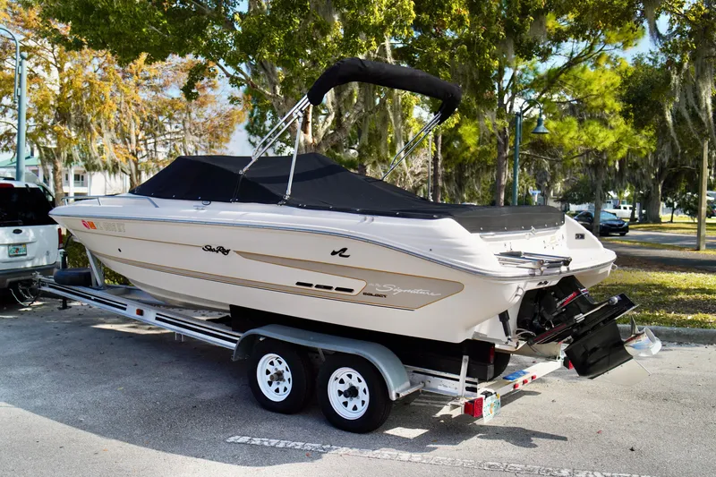 Slide: The Image of 1995 Sea Ray 200 Bow Rider boat on trailer, parked outdoors with trees in background. - 35