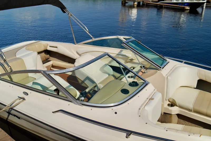 Slide: The Image of 1995 Sea Ray 200 Bow Rider boat interior with beige seating, docked on calm water. - 7