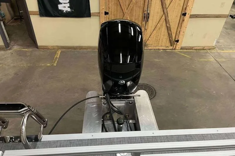 Slide: The Image of 2026 Sun Tracker Party Barge 22 RF DLX with outboard motor in a garage setting. - 3