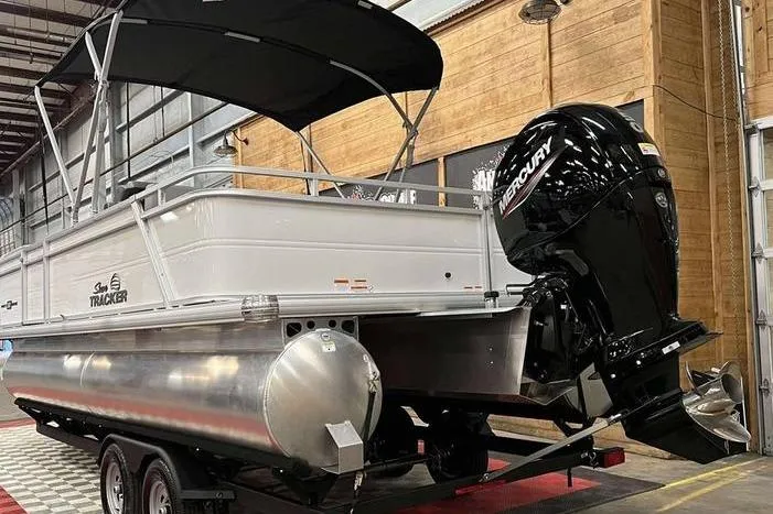 Slide: The Image of 2026 Sun Tracker Party Barge 22 RF DLX pontoon boat with Mercury outboard motor in a showroom. - 4
