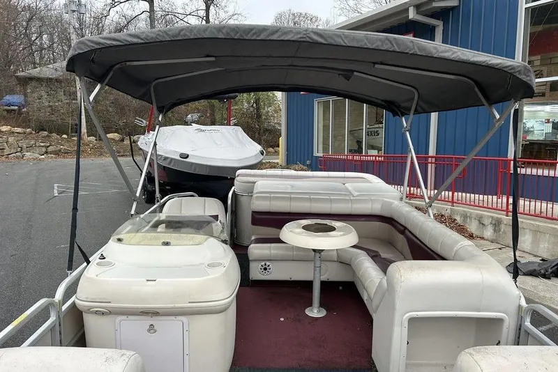 Slide: The Image of 2003 Sweetwater 2221 SC pontoon boat with canopy and seating, parked near a blue building. - 10