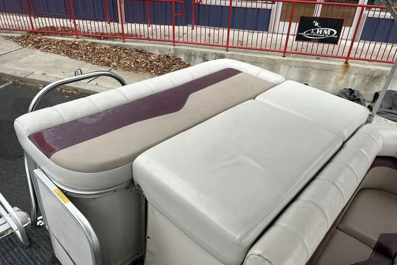 Slide: The Image of 2003 Sweetwater 2221 SC boat with cushioned seating and red railing in a marina setting. - 11