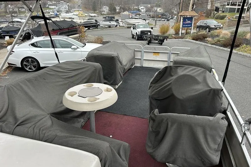 Slide: The Image of Pontoon boat interior with covered seats, Sweetwater 2221 SC, 2003 model, parked near vehicles. - 7