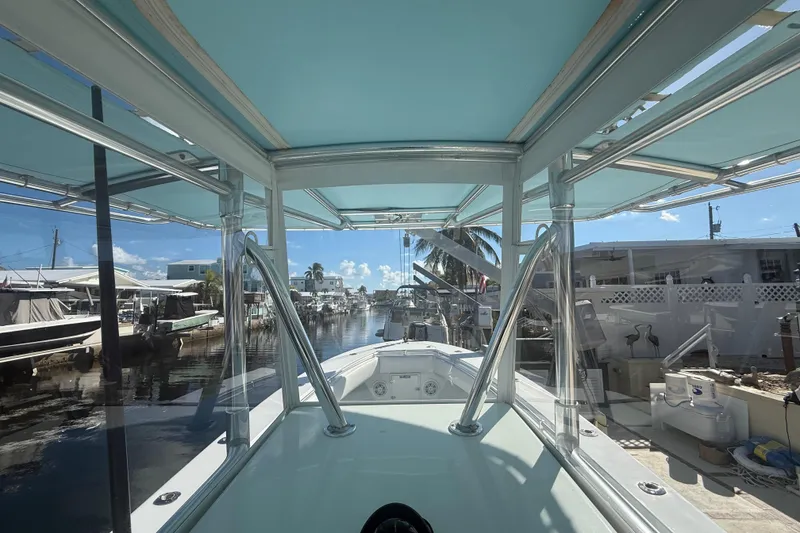 Slide: The Image of 2003 Contender 27 Open boat interior with console and rod holders, docked by waterfront homes. - 14