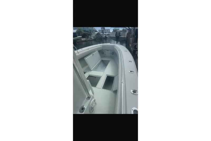 Slide: The Image of 2003 Contender 27 Open boat docked in a sunny marina, surrounded by waterfront homes. - 35