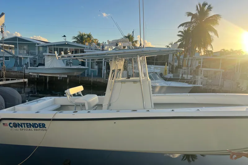 Slide: The Image of 2003 Contender 27 Open boat docked at sunset, featuring sleek design and palm trees in the background. - 65