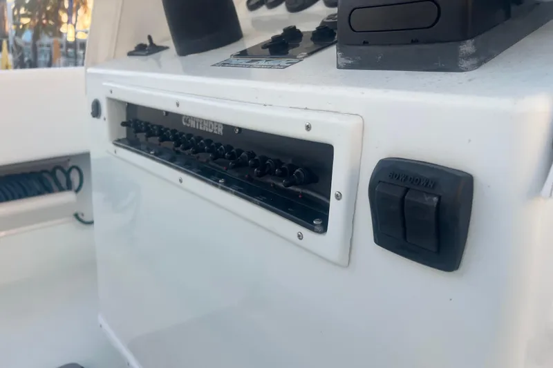 Slide: The Image of Control panel of a 2003 Contender 27 Open boat, featuring switches and buttons. - 69