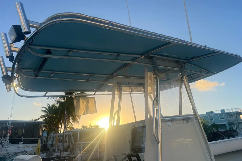 Slide: The Image of 2003 Contender 27 Open boat with T-top at sunset, docked near palm trees. - 70