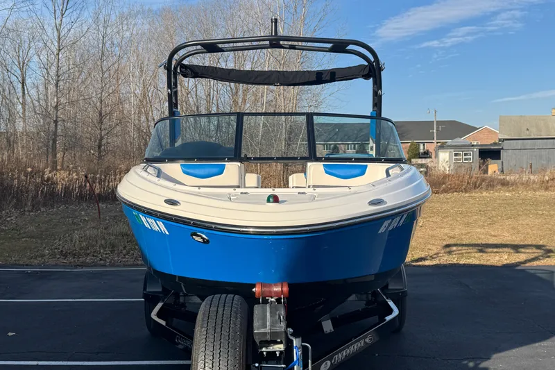Slide: The Image of 2018 Chaparral Vortex 203 VRX boat on trailer, blue and white, parked outdoors. - 2