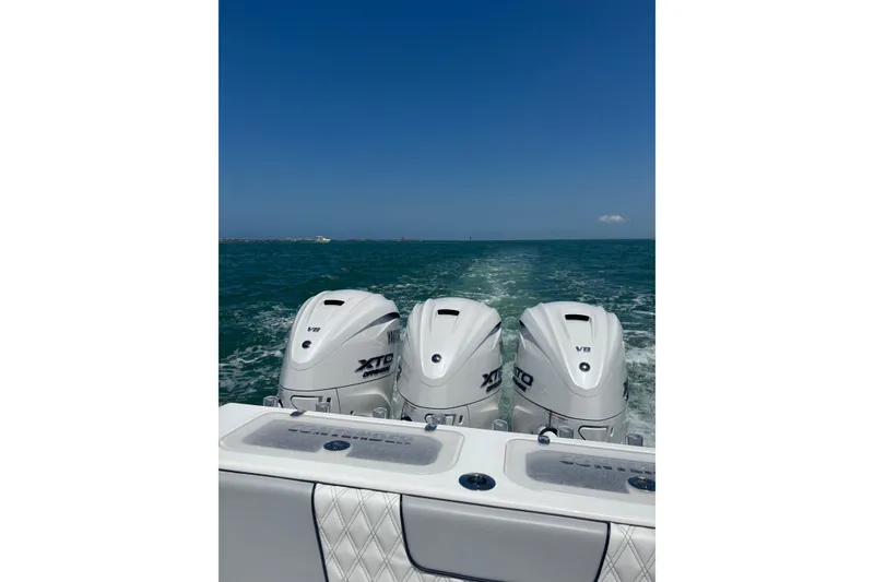 Slide: The Image of 2025 Contender 39 ST boat with triple outboard engines cruising on open water. - 5