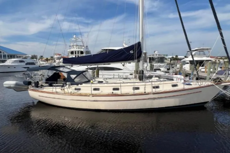 The Image of 1994 Island Packet 44 cutter sailboat docked in a marina under a clear sky. - 0
