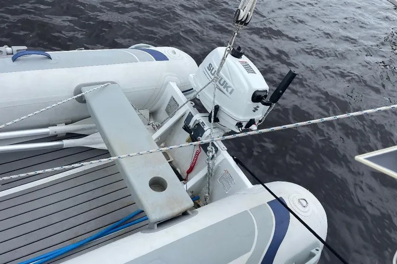 Slide: The Image of Inflatable boat with Suzuki outboard motor, docked beside Island Packet 44 cutter, 1994 model. - 44