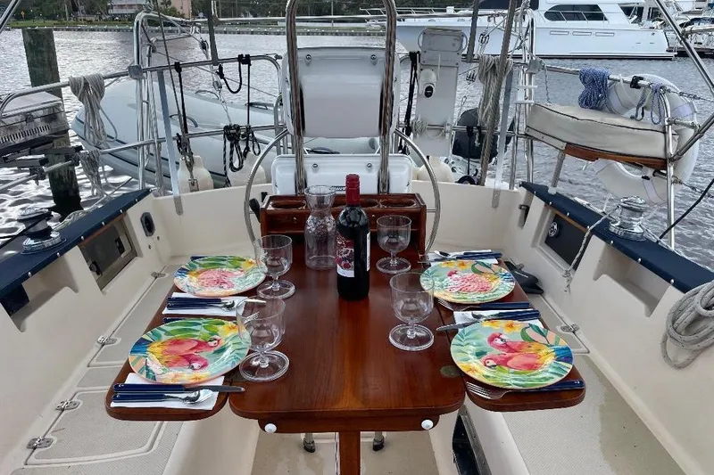 Slide: The Image of Dining setup on 1994 Island Packet 44 cutter yacht, featuring colorful plates and wine. - 47