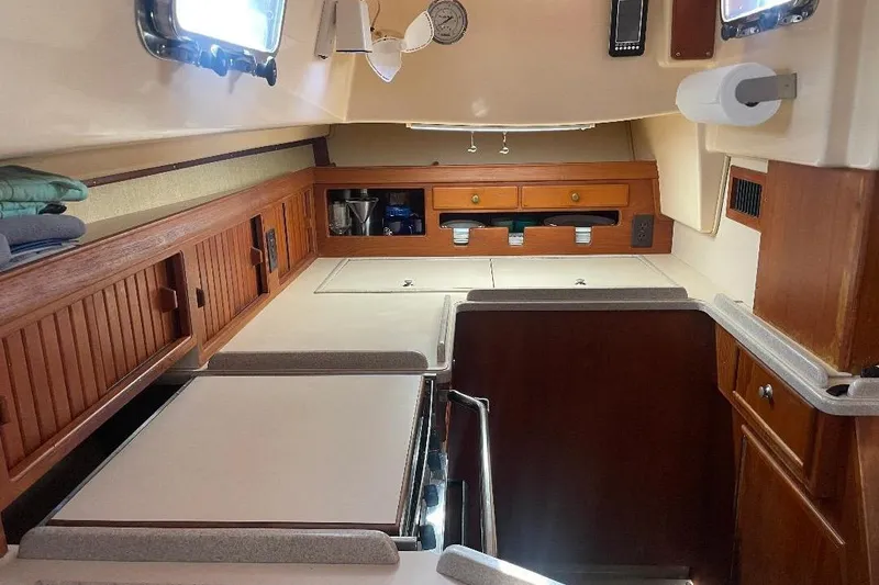 Slide: The Image of Interior of 1994 Island Packet 44 cutter sailboat, featuring wooden cabinetry and compact design. - 77