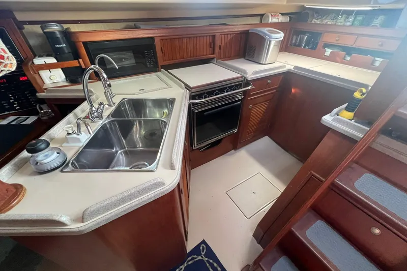 Slide: The Image of 1994 Island Packet 44 cutter kitchen with dual sink, stove, and wooden cabinetry. - 78