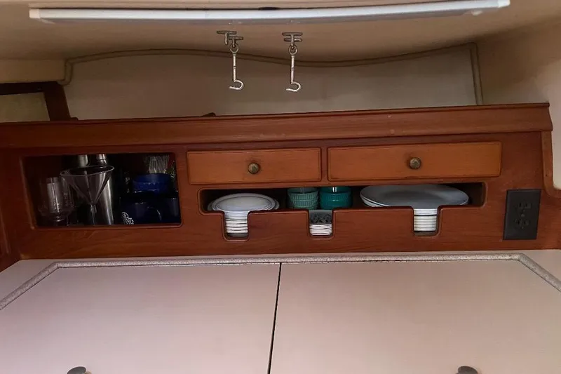 Slide: The Image of Interior of 1994 Island Packet 44 cutter with wooden cabinets and kitchenware storage. - 80