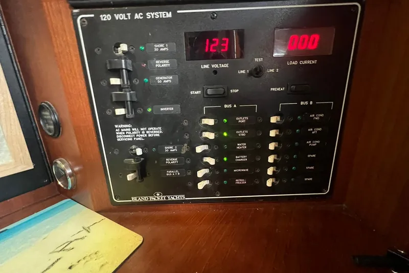 Slide: The Image of Electrical panel of a 1994 Island Packet 44 cutter yacht, showing 120V AC system controls. - 87