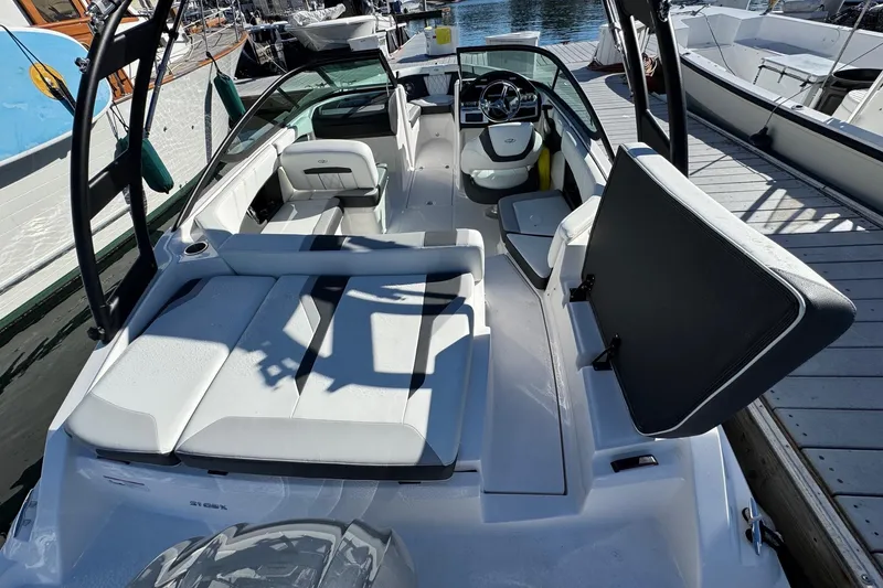 Slide: The Image of 2026 Regal 21 OBX boat interior with seating and steering wheel at a marina. - 13